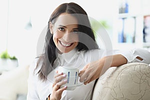 Beautiful brunette young woman chilling with cup of hot drink photo