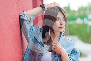 Portrait of beautiful brunette young woman with makeup in denim casual style standing, posing with hand on head and looking away