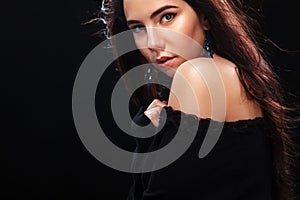 Portrait of beautiful brunnete girl, on black background. Pretty girl model. A brunette woman in a black dress.