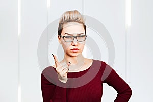 Portrait of beautiful business woman in glasses showing finger up