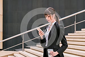 Portrait of beautiful business woman using smartphone on her way to work