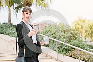 Portrait of beautiful business woman using smartphone on her way to work