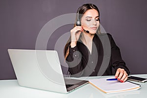 Portrait of beautiful business woman working at her desk with headset and laptop in office