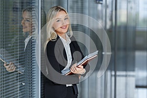 Portrait of beautiful businesswoman smiling and standing with folder in the office