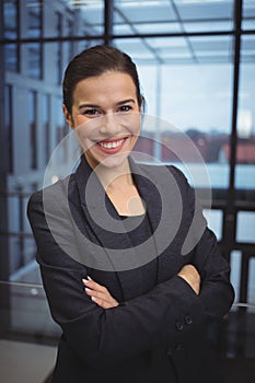 Portrait of beautiful businesswoman standing with arms crossed in corridor