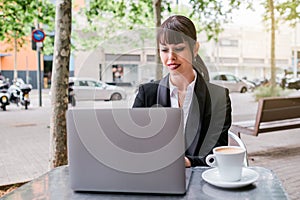 Portrait of beautiful businesswoman using laptop sitting in coffee shop outdoors