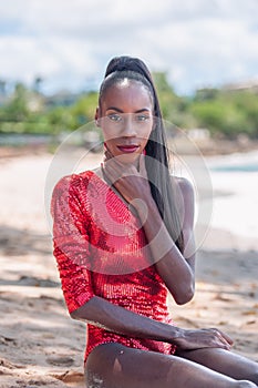 Portrait of Beautiful Caribbean Adult Teen in Barbados. Wearing Red Bikini and Sitting on a tropical beach. Caribbean Sea in