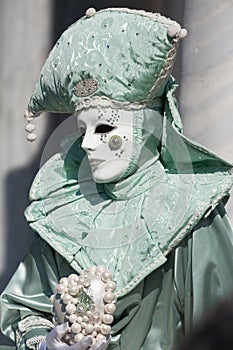 Portrait of beautiful carnival mask with acquamarine green costume and a heart of pearls.