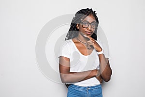 Portrait of beautiful casually dressed young afro american woman in round glasses having doubtful expression, looking away in