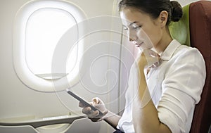 Portrait of beautiful caucasian businesswoman female passenger of airplane using networks via smartphone wifi on board.