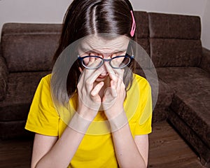 Portrait of a beautiful caucasian girl in a yellow T-shirt wipes her eyes with her hands, the girl is upset, crying