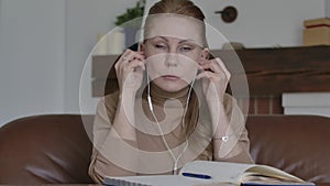 Portrait of beautiful Caucasian woman putting on earphones, waving at camera and smiling. Young lady greeting in online