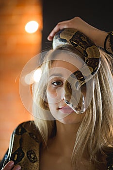 Portrait of beautiful caucasian woman with a python on her face