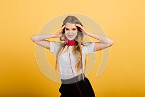 Portrait of beautiful cheerful female with long hair smiling looking at camera over yellow back