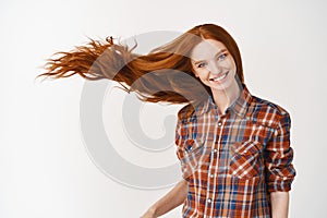 Portrait of beautiful cheerful redhead girl with flying curly hair smiling laughing looking at camera over white