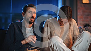 Portrait of Beautiful Couple Spending Time at Home, Sitting on a Couch, Watching Scary TV Show in