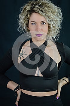 Portrait of a beautiful curly blonde woman holding her hands on her hips as a sign of expectation