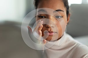 Portrait of beautiful curvy woman, looking at small round makeup mirror at home.