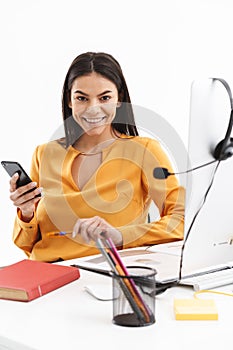 Portrait of beautiful customer supporter woman holding smartphone while working in call center