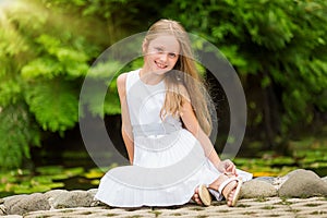 Portrait of a beautiful cute girl with long hair in a park. Girl looking at the camera. Summer portrait