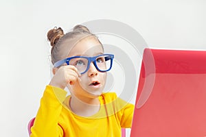 Portrait of beautiful cute little girl with glasses using laptop computer