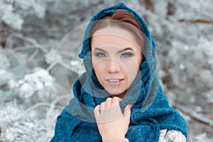 Portrait of a beautiful cute red-haired girl in the winter forest