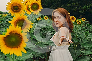 Portrait of a beautiful, cute, sexy red-haired girl in a white dress with sunflower flowers. Emotion of pleasure, freedom concept