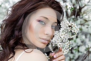 Portrait beautiful cute sweet girl bride with gentle eye make-up full lips in white light dress walks in lush gard