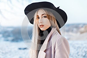 Portrait of a beautiful cute woman with natural make-up with clean skin in a stylish elegant hat in a pink coat