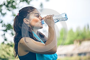Portrait of beautiful dark-haired girl drinking water at summer