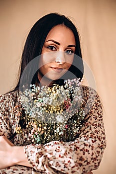 Portrait of a beautiful dark-haired girl. A girl with a bouquet of dry colourful flowers