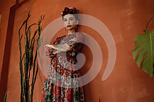 Portrait of beautiful dark-haired woman with crown braid hairstyle and floral head band wearing chic chiffon dress with basque