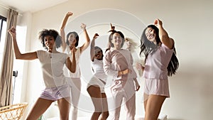 Portrait beautiful diverse girls dancing on bed together