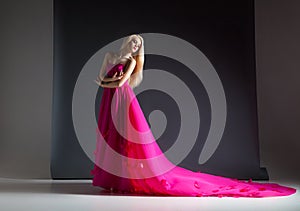 Portrait of beautiful and elegant blonde woman posing in pink dress