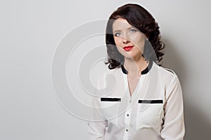 Portrait of beautiful elegant woman in a bright white shirt with bright makeup and red lipstick on a white background in studio