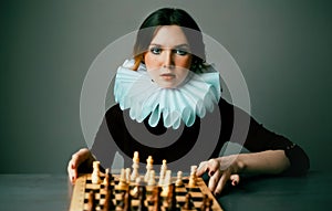 Portrait of a beautiful elegant woman in a white jabot who is playing chess. Jester. The Queen\'s gambit. Checkmate