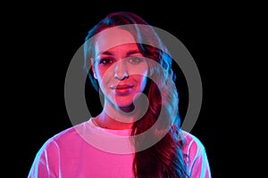 Portrait of beautiful, elegant young woman with curly hair posing with smile against black studio background in neon