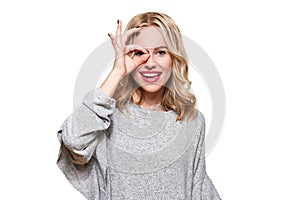 Portrait of beautiful excited woman in casual clothing smiling and showing ok sign at camera isolated over white.