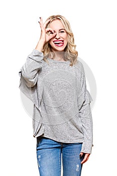 Portrait of beautiful excited woman in casual clothing smiling and showing ok sign at camera isolated over white background.
