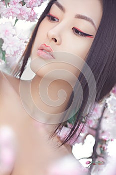 Portrait of a beautiful fantasy asian girl outdoors against natural spring flower background.