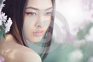 Portrait of a beautiful fantasy asian girl outdoors against natural spring flower background.