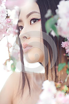 Portrait of a beautiful fantasy asian girl outdoors against natural spring flower background.