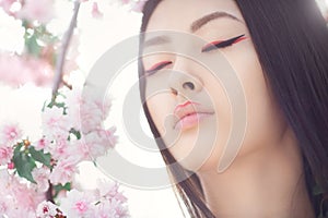 Portrait of a beautiful fantasy asian girl outdoors against natural spring flower background.