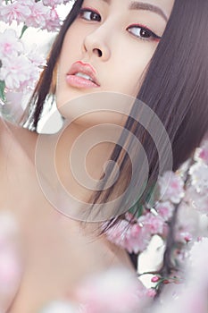 Portrait of a beautiful fantasy asian girl outdoors against natural spring flower background.