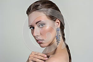 Portrait of a beautiful fashion glamour girl brown-haired in the studio with big silver earrings