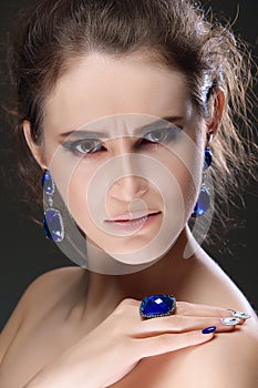 Portrait of beautiful fashion model with bijouterie. Ear-rings, finger ring and necklace with big crystals