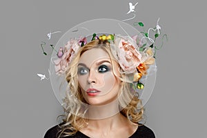 Portrait of a beautiful fashion model with red lips and blue eyes with coronet from flowers in curly blonde hair