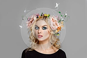 Portrait of a beautiful fashion model with red lips and blue eyes with coronet from flowers in curly blonde hair