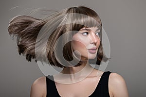 Portrait of beautiful fashion woman with bob hairstyle. Flying hairs up. Surf background