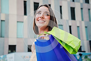 Portrait of beautiful fashion woman going shopping carrying colorful paper bags walking and looking up with a smiley
